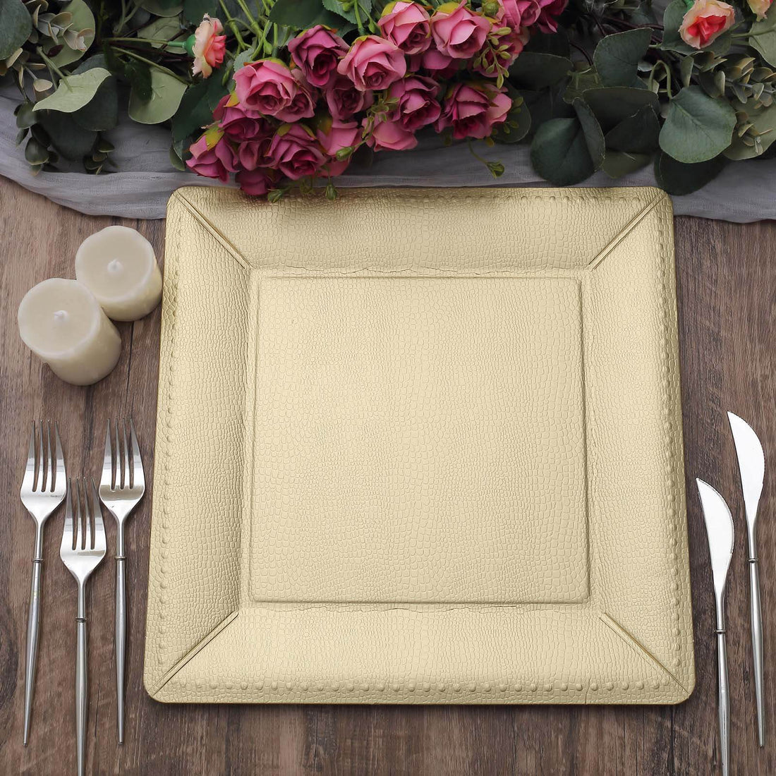 Gold textured dinner plate with silver cutlery and candles, surrounded by roses.