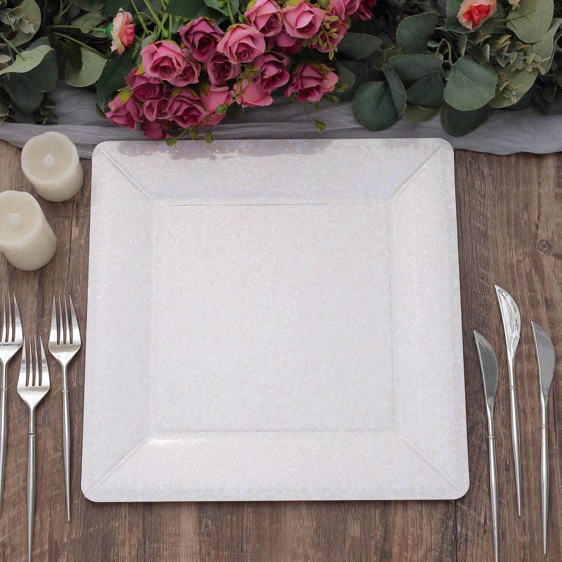 Elegant square white dinner plate with floral design, set on rustic wooden table.