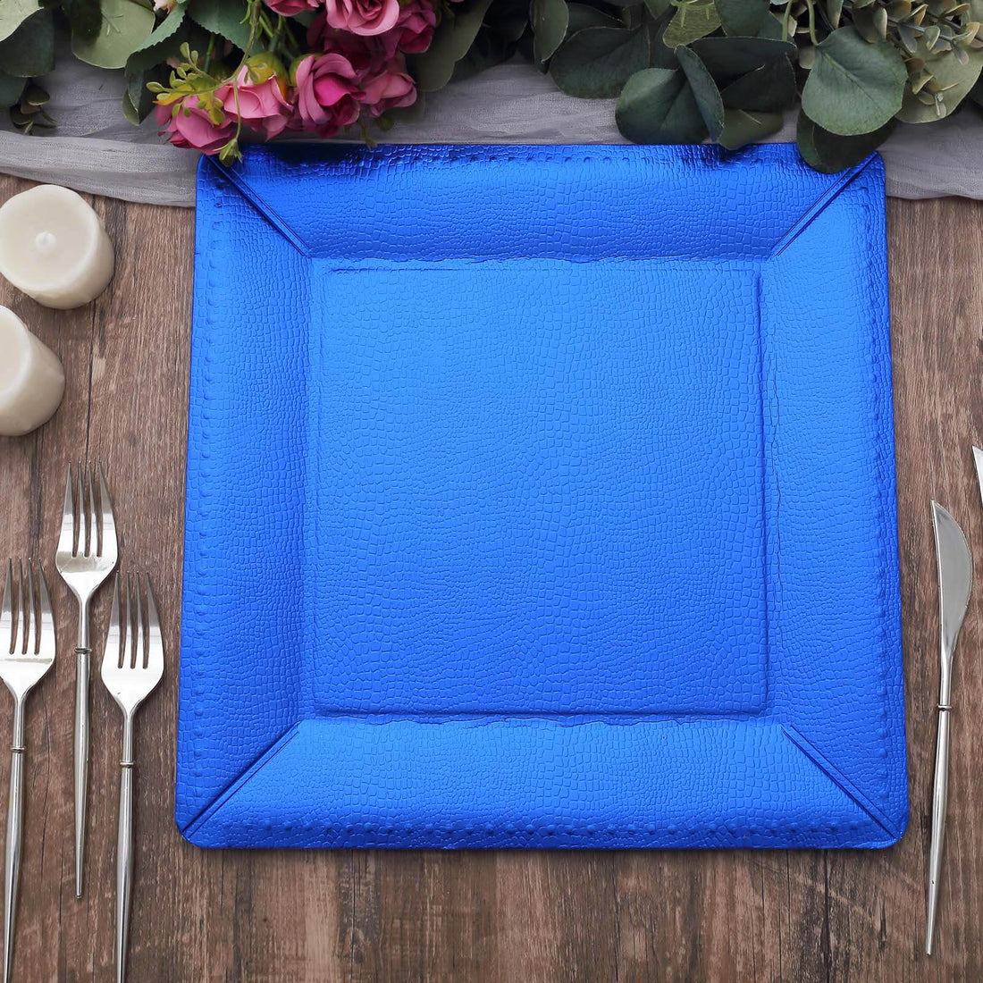 Blue textured serving platter on a wooden table with cutlery and candles.
