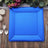 Blue textured serving platter on a wooden table with cutlery and candles.