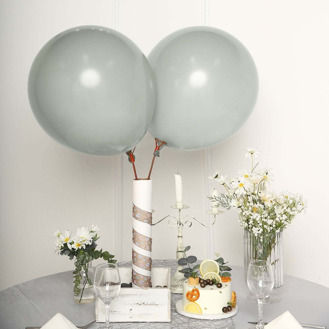 Gray balloons with a cake and flowers on a table setting.