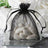 Black organza bag filled with white candies on a reflective surface.