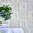 Textured white wall panels with floral patterns and greenery in a styled setting.