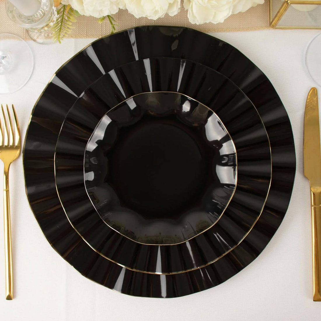 Elegant black plates with gold trim arranged on a table setting.