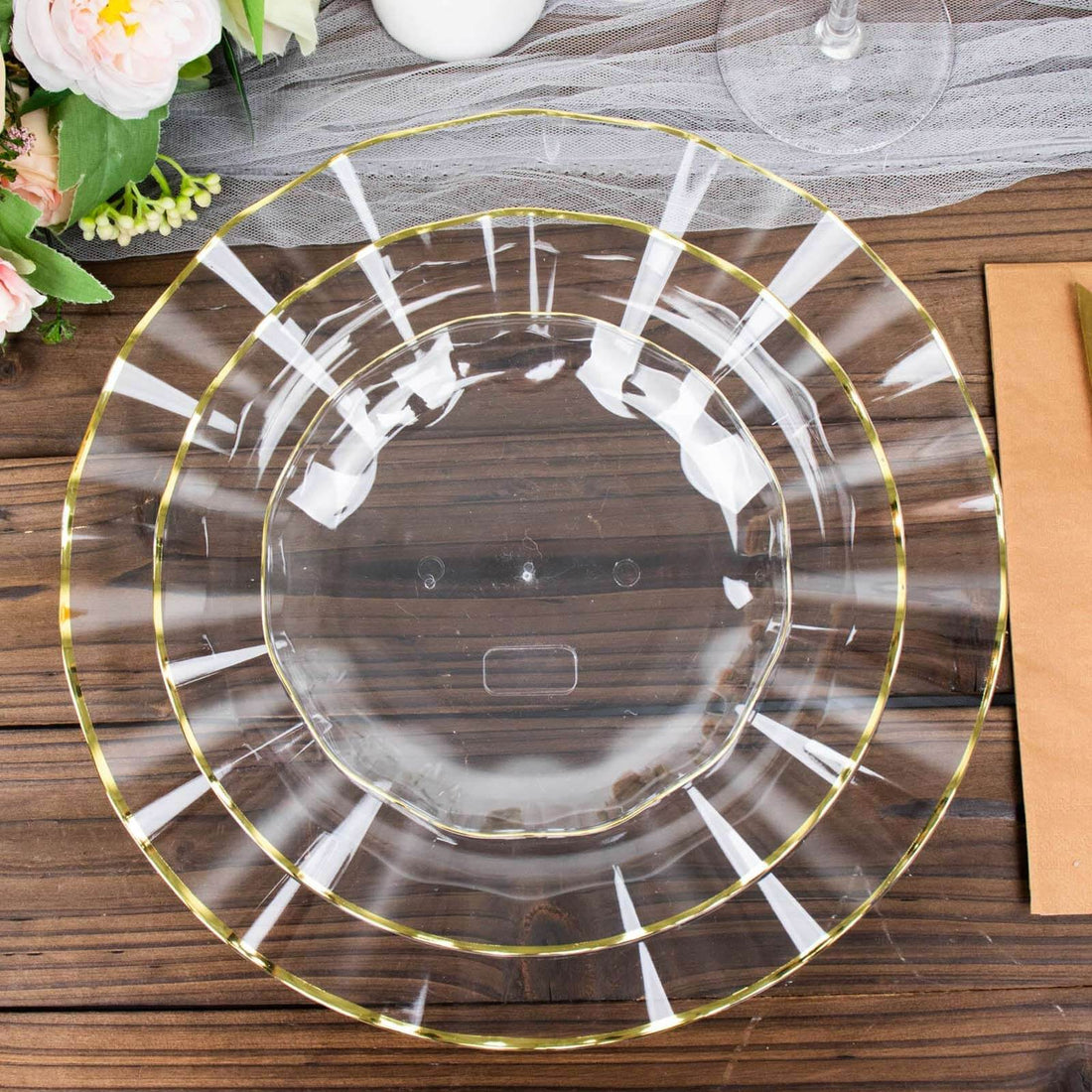 Clear glass charger plate with gold rim on a wooden surface.