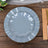 Gray decorative plate with gold trim on a wooden table setting.