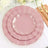 Pink scalloped plates set with gold rim on a table setting.