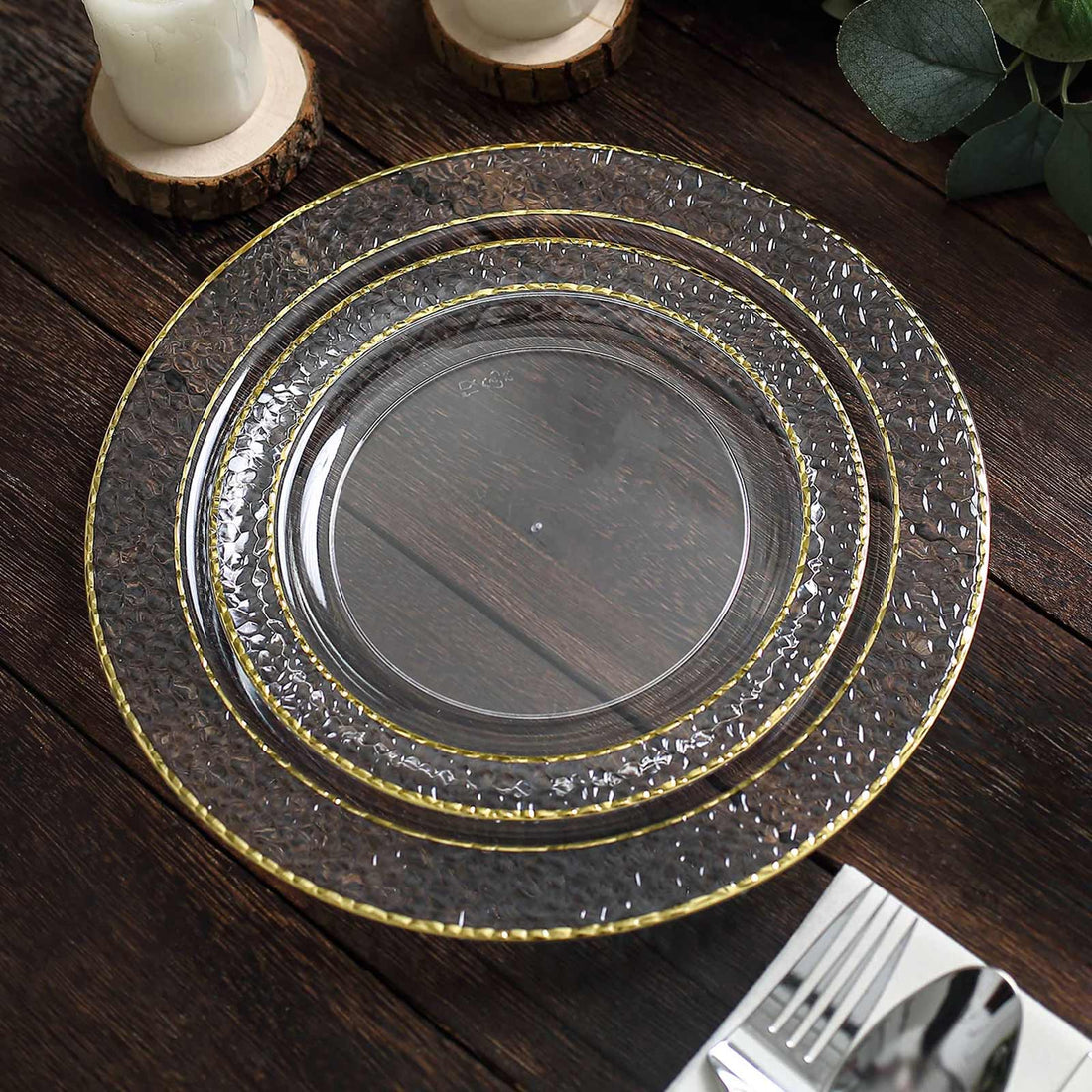 Elegant clear charger plates with textured design and gold trim on a rustic wooden table.