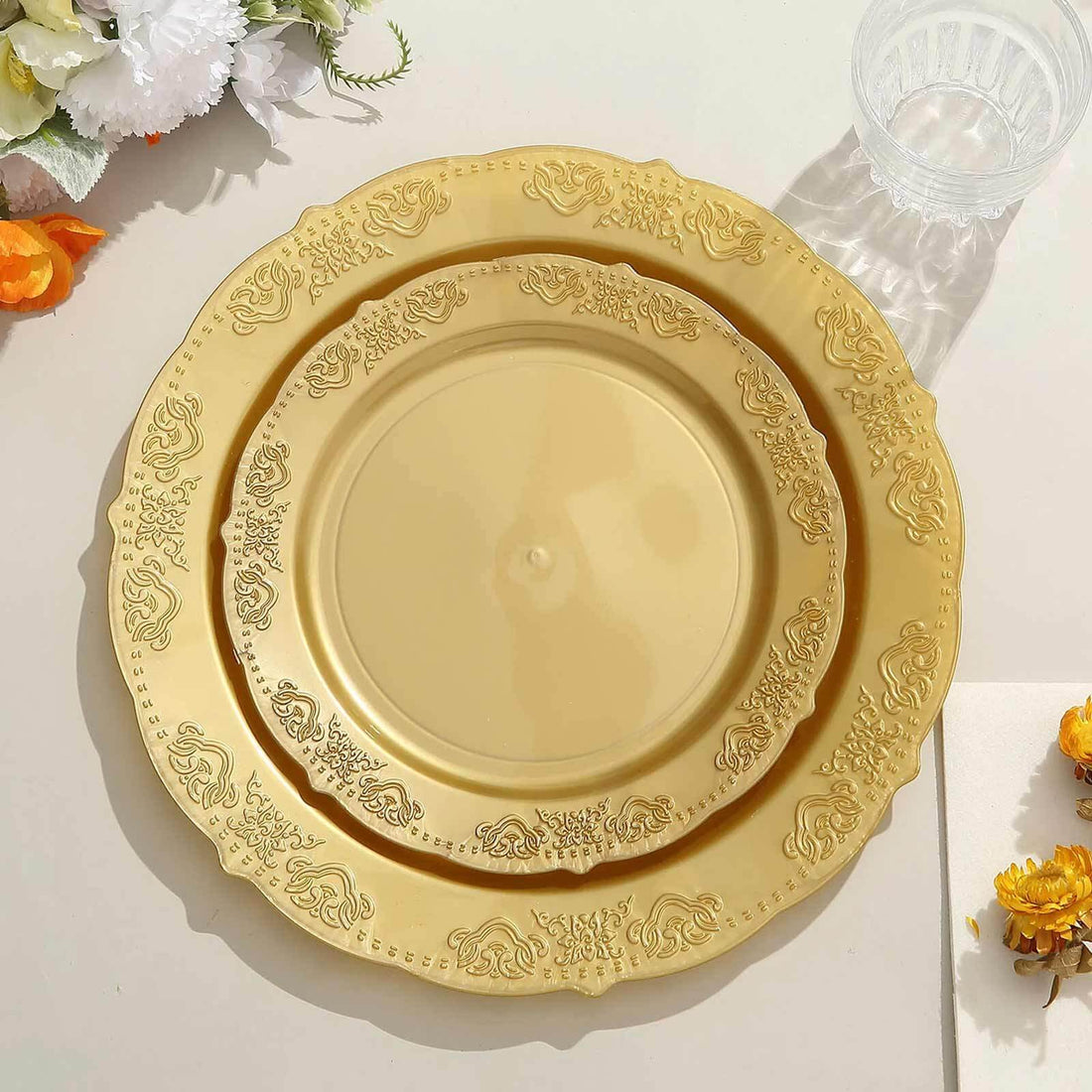 Gold decorative plates stacked on a table with floral accents.