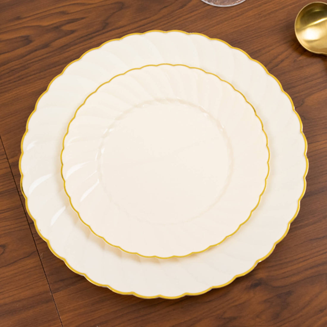 Elegant cream plates with gold trim, stacked on a wooden table.