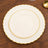 Elegant cream plates with gold trim, stacked on a wooden table.