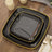 Black square plates with yellow trim on a rustic wooden table.