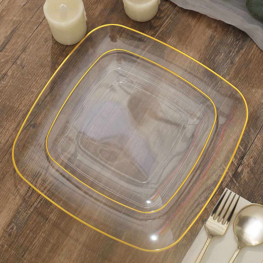 Clear square plate with gold trim on a wooden table setting.