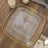 Clear square plate with gold trim on a wooden table setting.