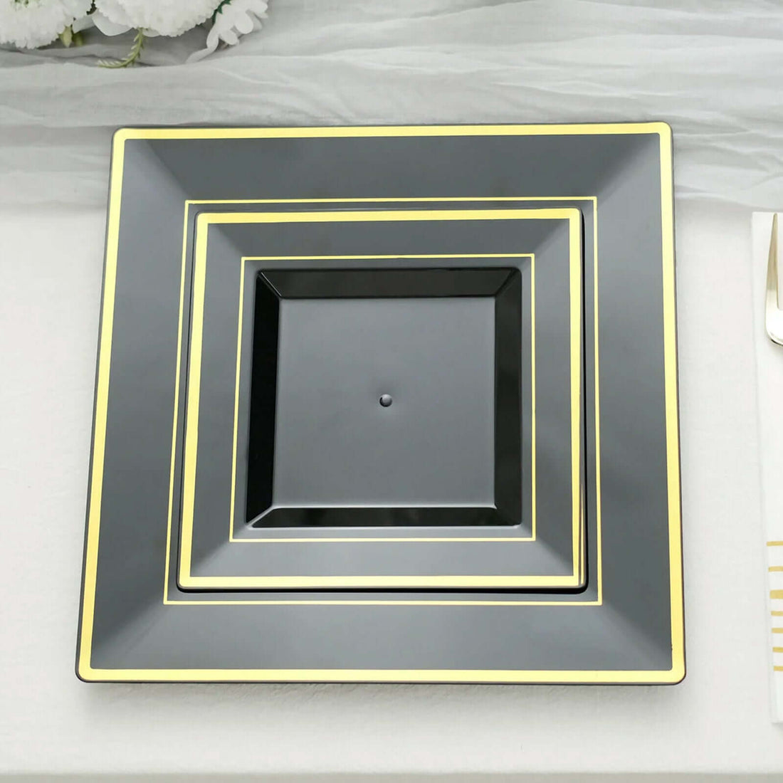Black square plates with gold trim in three stacked sizes.