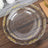 Clear decorative plate with gold accents on a wooden surface.