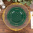 Elegant green and gold decorative plates stacked on a wooden table.