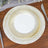 Elegant gold-striped dinner plate on a wooden table setting.