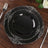 Elegant black plate with ornate silver detailing on a wooden table.
