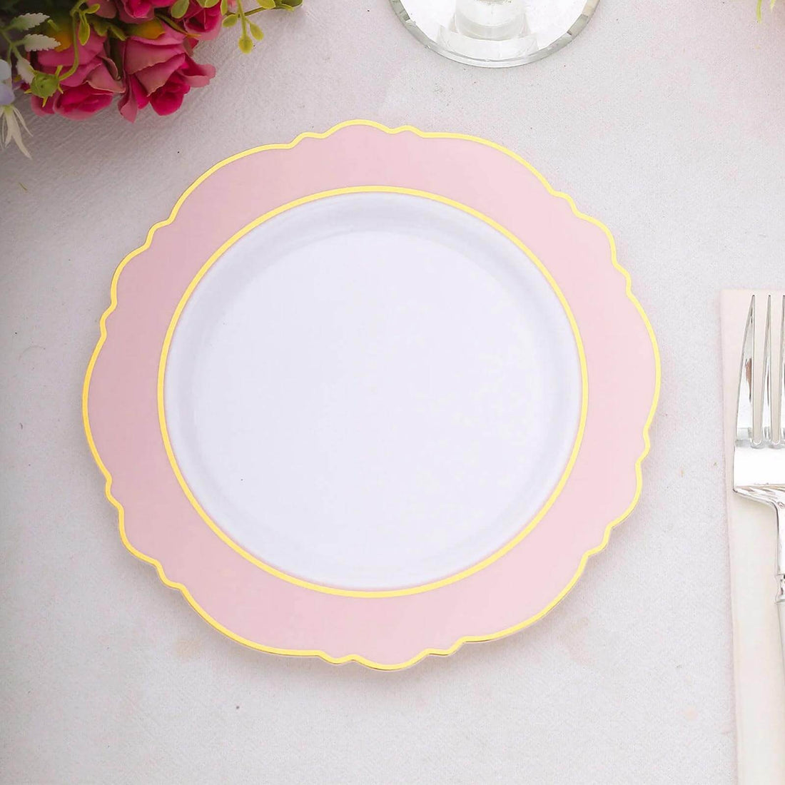 Pink scalloped plate with gold trim on a light background.