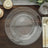 Clear charger plate with beaded rim on a wooden table setting.