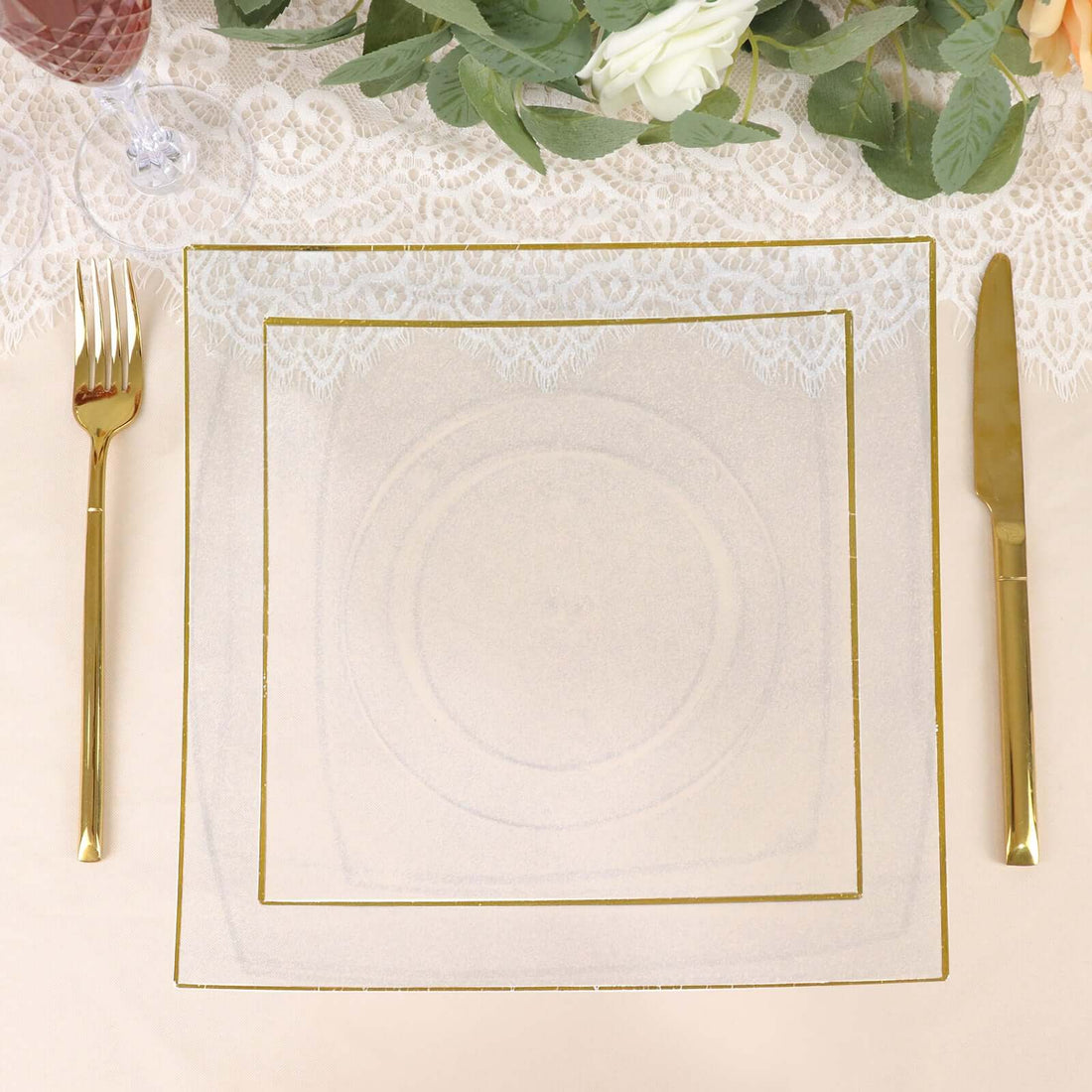 Elegant gold-trimmed plate set on a table with lace and floral decor.