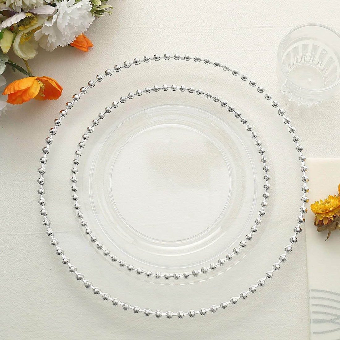 Clear glass plates with beaded edges, arranged in three sizes.