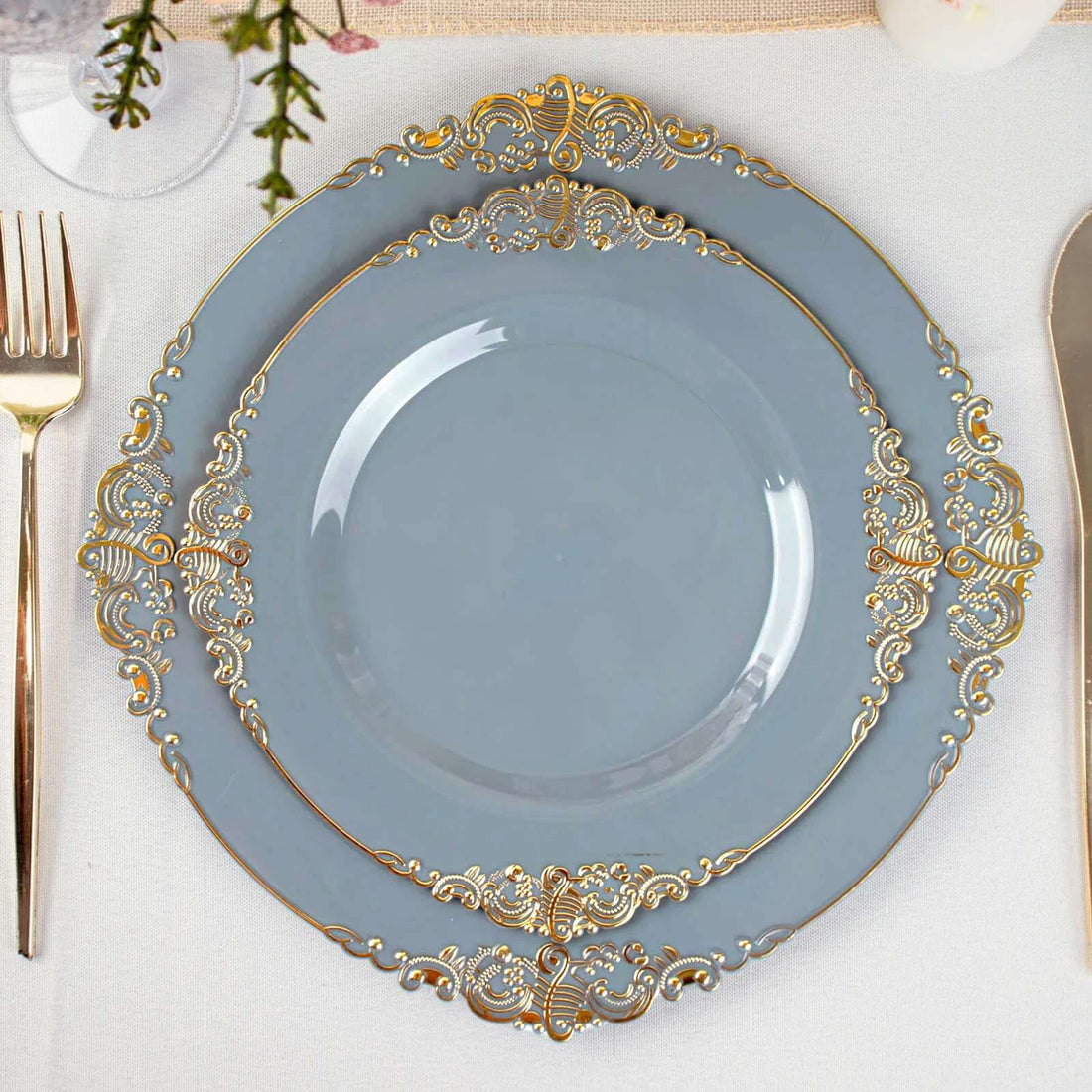 Elegant blue plate with gold ornate trim on a dining table setting.