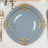Elegant blue plate with gold ornate trim on a dining table setting.