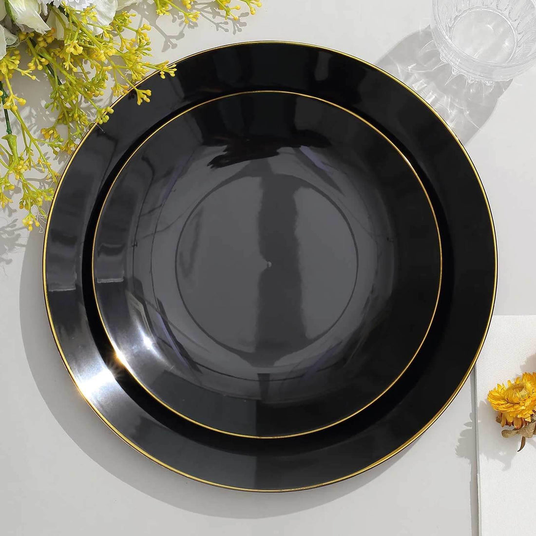 Elegant black plates with gold rim, stacked on a light surface.