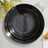 Elegant black plates with gold rim, stacked on a light surface.