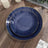 Navy blue ceramic plates with gold trim stacked on a wooden table.