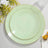 Green plates with gold trim on a light surface, surrounded by flowers.