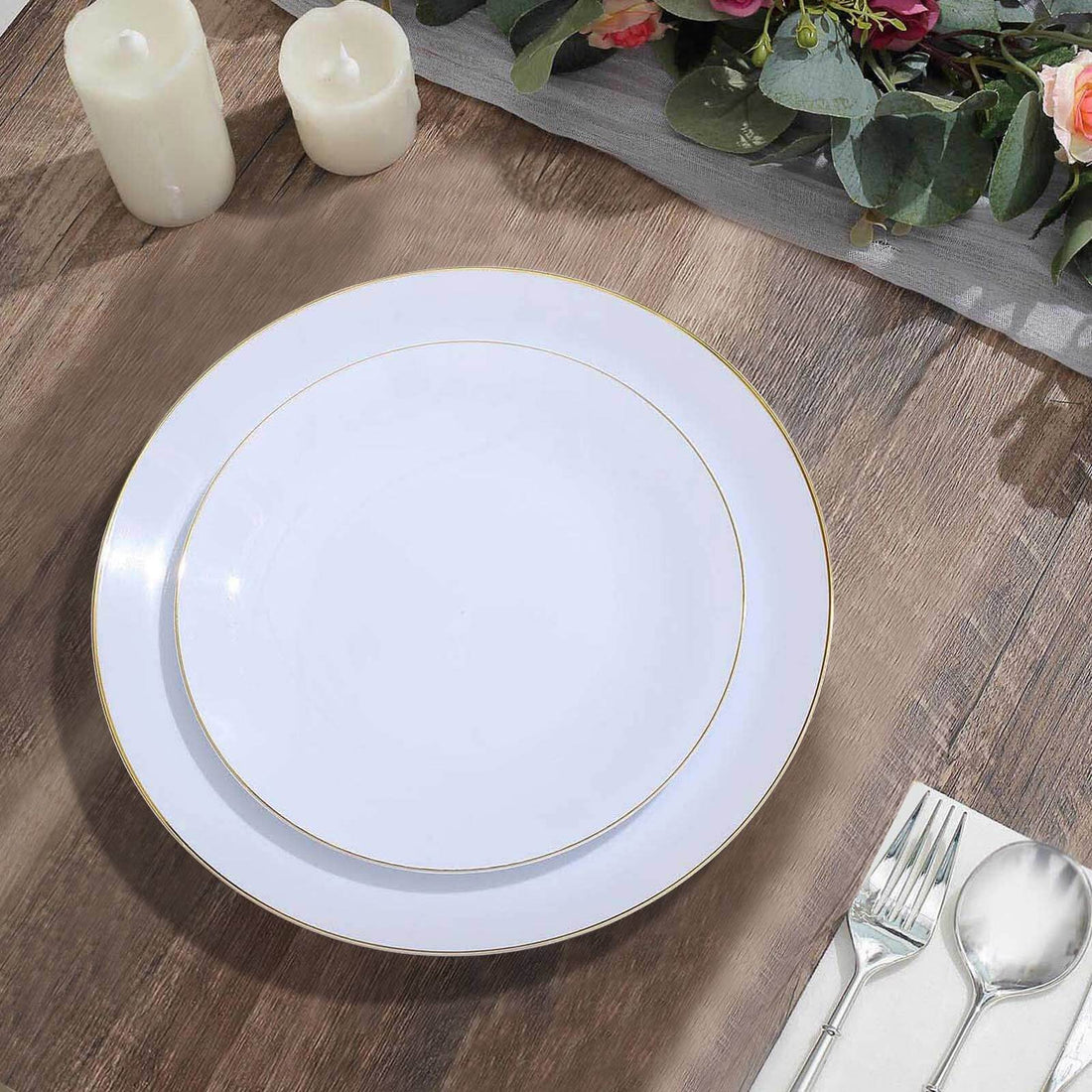 Elegant white dinner plates with gold trim on a rustic wooden table setting.