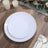 Elegant white dinner plates with gold trim on a rustic wooden table setting.