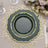 Elegant green and gold decorative plates arranged on a lace table mat.