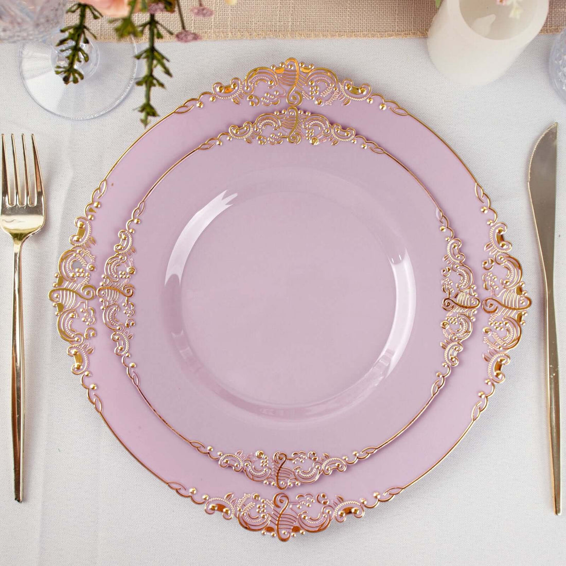 Elegant pink plate with gold ornate border on a dining table setting.