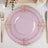 Elegant pink plate with gold ornate border on a dining table setting.