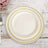 Elegant white dinner plates with gold trim stacked on a rustic wooden table.