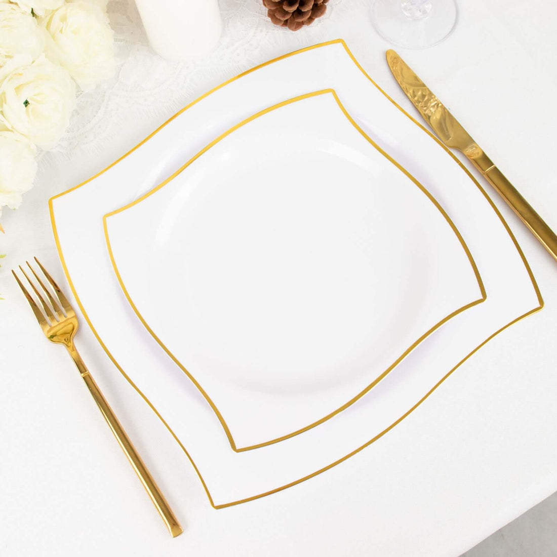 Elegant white plates with gold trim on a dining table setting.