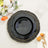 Black scalloped decorative plate with gold trim on floral backdrop