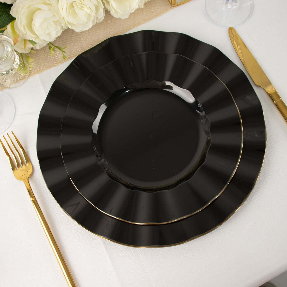 Black decorative plates with gold trim on a dining table setting.