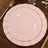 Pink dinner plates with gold trim on a wooden table.