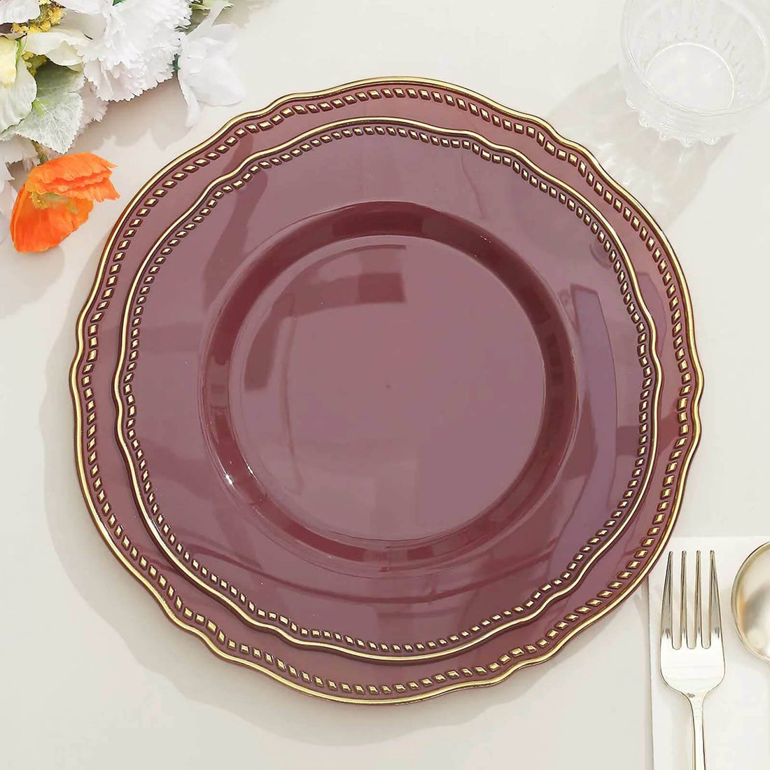 Burgundy scalloped dinner plate with gold trim on table setting