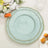 Elegant aqua plate with ornate gold trim, styled with florals and decor.
