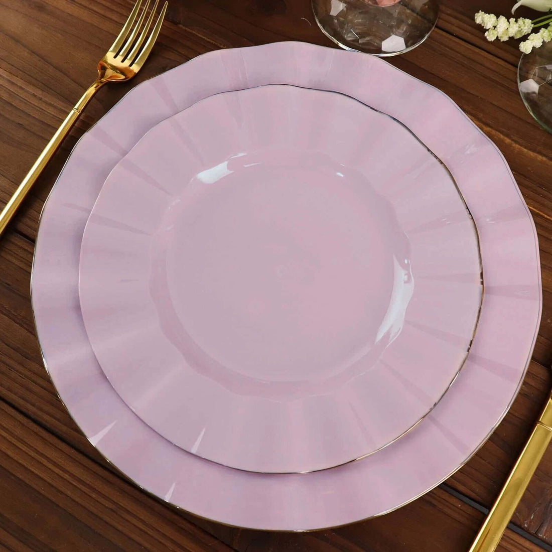Pink decorative plates set with gold rim on a wooden table.