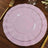Pink decorative plates set with gold rim on a wooden table.