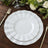 Elegant white dinner plates with gold trim on a wooden table setting.