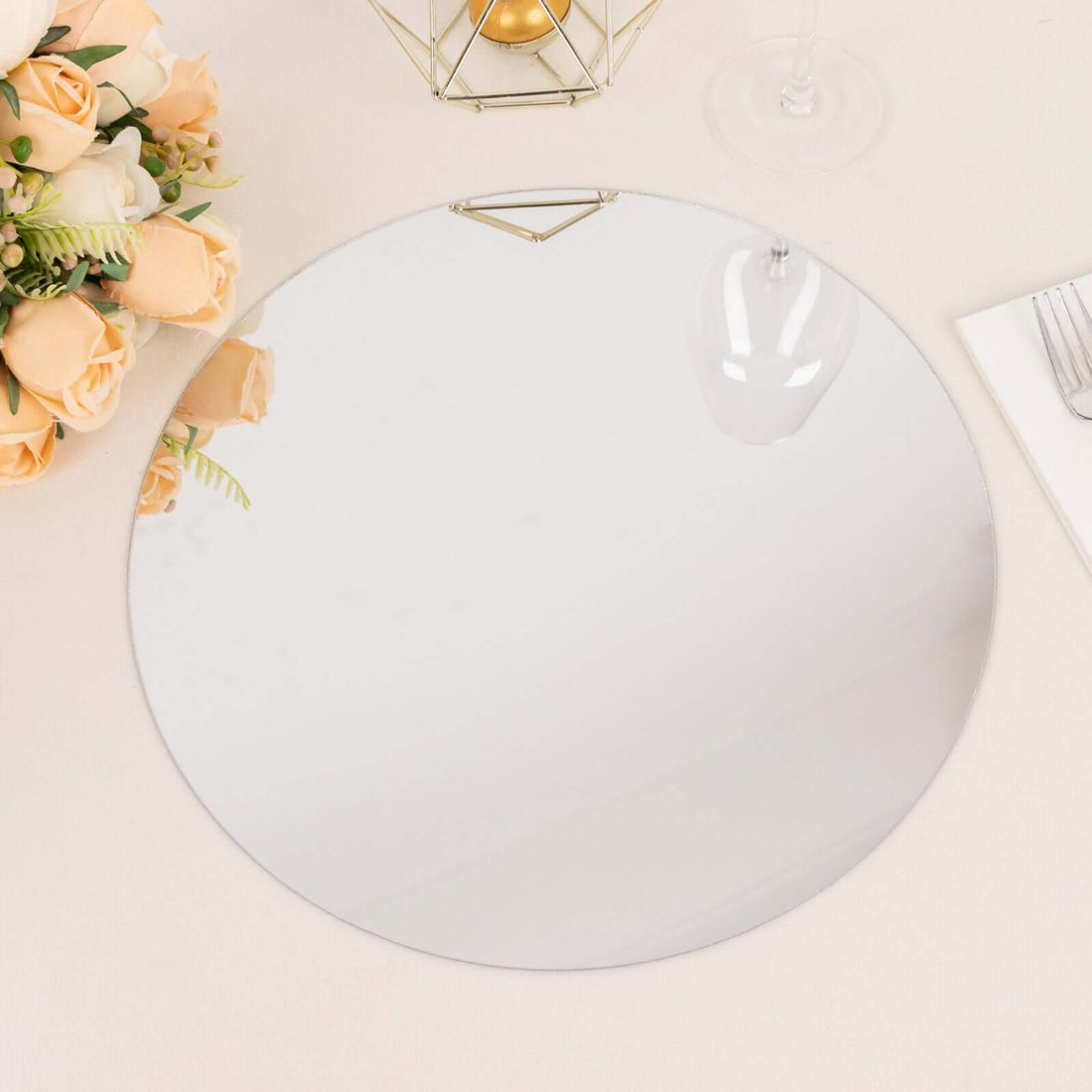 Round decorative mirror with a gold handle on a light surface.