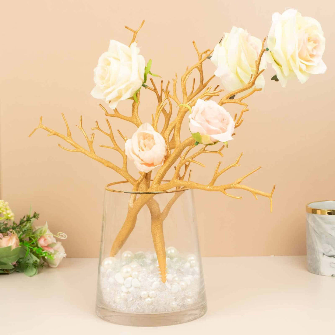 Gold branch floral arrangement in a glass vase with decorative pearls.